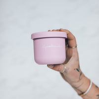 Hand holding a pink Mini Silicone Pot Container with the lid on