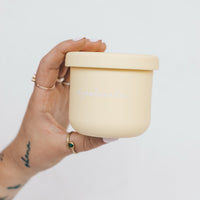 Hand holding a yellow Mini Silicone Pot Container with the lid on