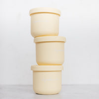 Three yellow Mini Silicone Pot Containers stacked in a column with their lids on