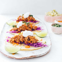 Slow cooked pulled filling served on flatbreads with slaw and lime, from Modern Slow Cooker