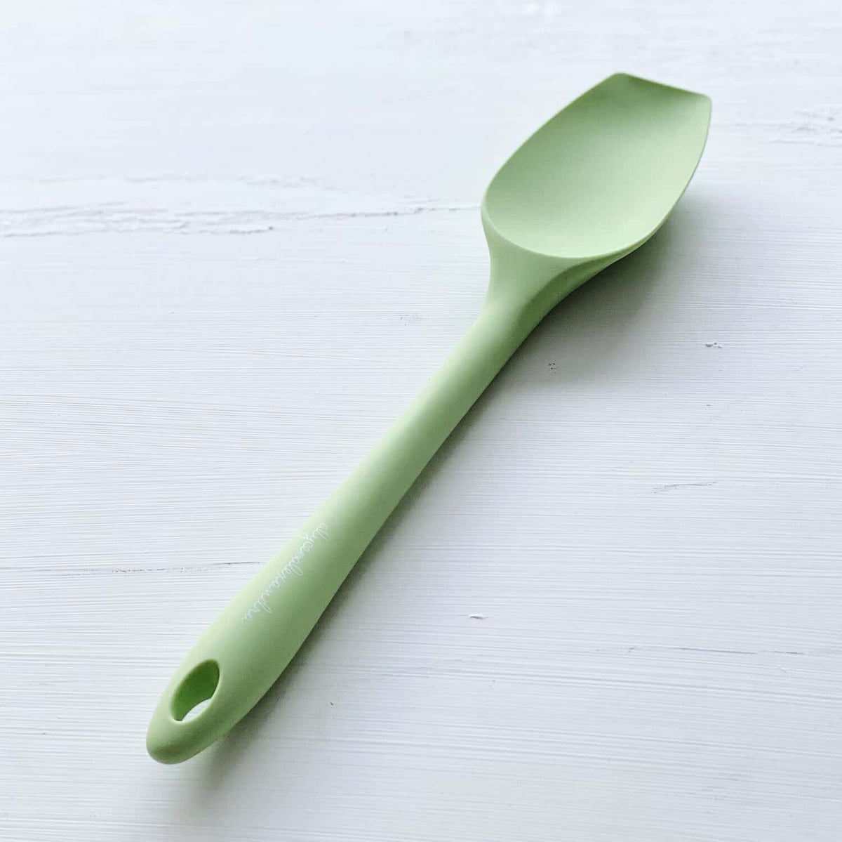 Sage green Slow Cooker Spatula laid flat on a pale surface