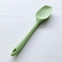 Sage green Slow Cooker Spatula laid flat on a pale surface
