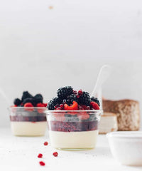 Jars of layered yoghurt and berry compote with fresh berries alongside, from Modern Slow Cooker