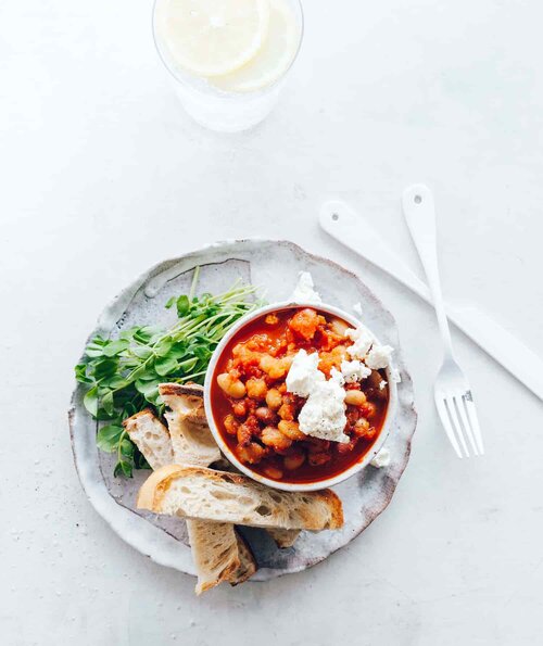 Bowl of slow cooked stew topped with yoghurt and herbs, served with flatbread, from Modern Slow Cooker