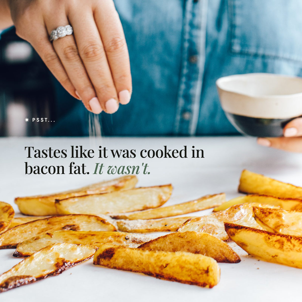 Hand sprinkling No-Bacon Bacon Salt from a small bowl over golden roasted potato wedges; tastes like it was cooked in bacon fat, but it wasn't