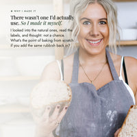 Alyce Alexandra in a linen apron holding a small sourdough loaf in her kitchen, on why she created No-Nasty Bread Improver after reading the labels on the natural improvers already on the market