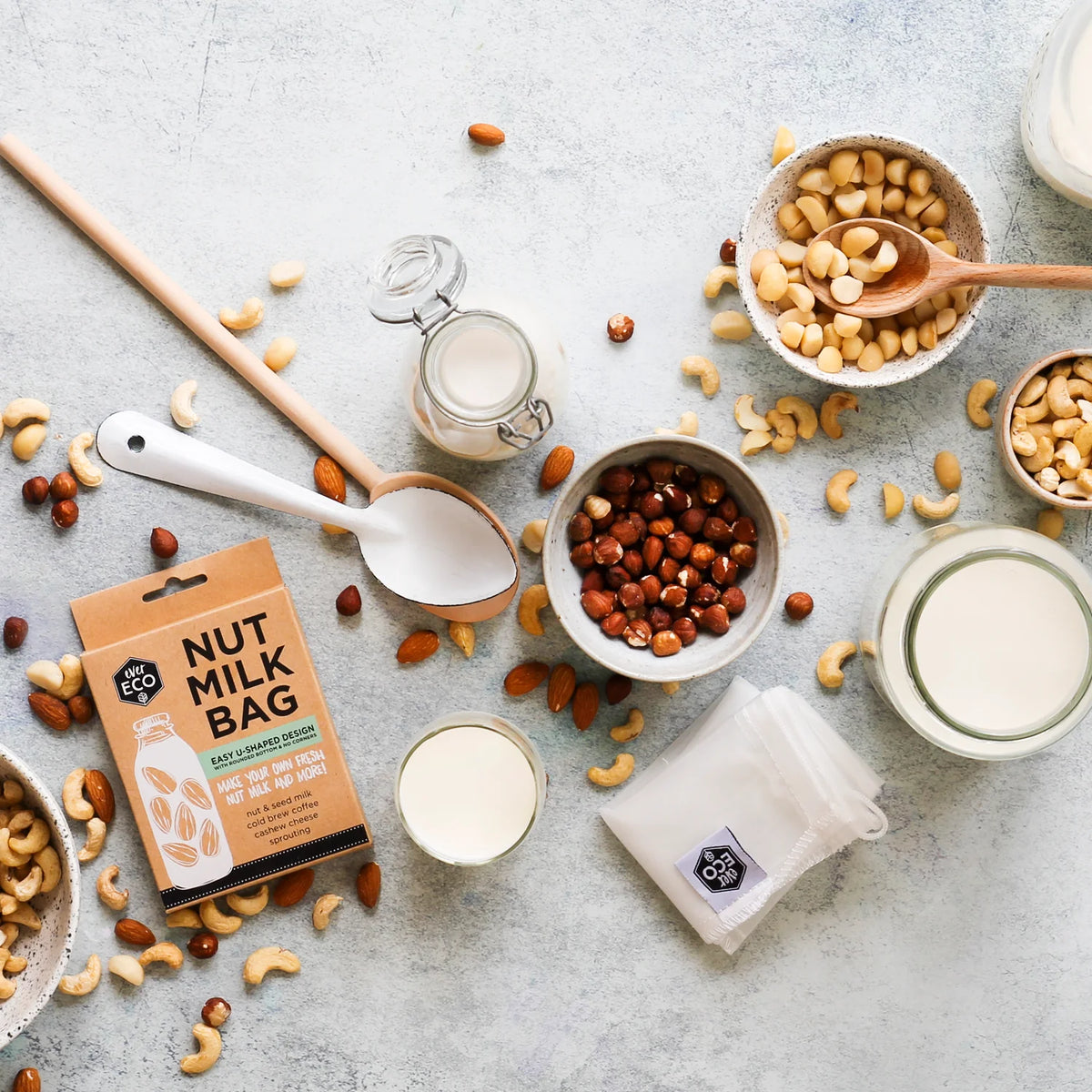 Nut Milk Bag pack surrounded by cashews, hazelnuts and glasses of nut milk