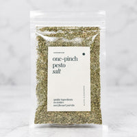 Alyce's One-Pinch Pesto Salt in a clear 100g packet with a cream label and deep green lettering, the green basil-flecked salt visible through the front
