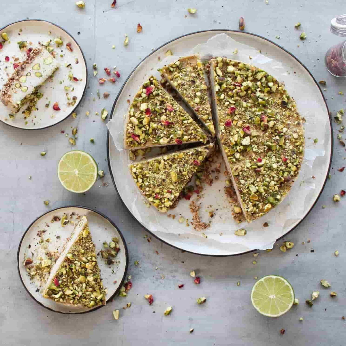 Lime and pistachio cake cut into wedges on a plate with fresh limes, from the Paleo Class Booklet