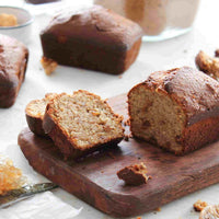 Sliced paleo loaf on a wooden board with a knife, from the Paleo Class Booklet