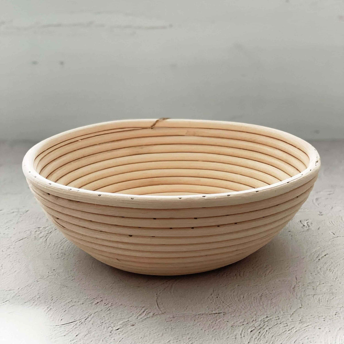 Empty round rattan proving basket showing its concentric coil pattern