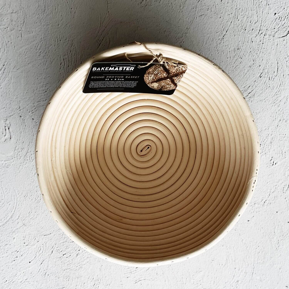 Round rattan proving basket with its Bakemaster tag, seen from above