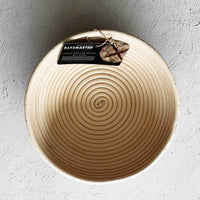 Round rattan proving basket with its Bakemaster tag, seen from above