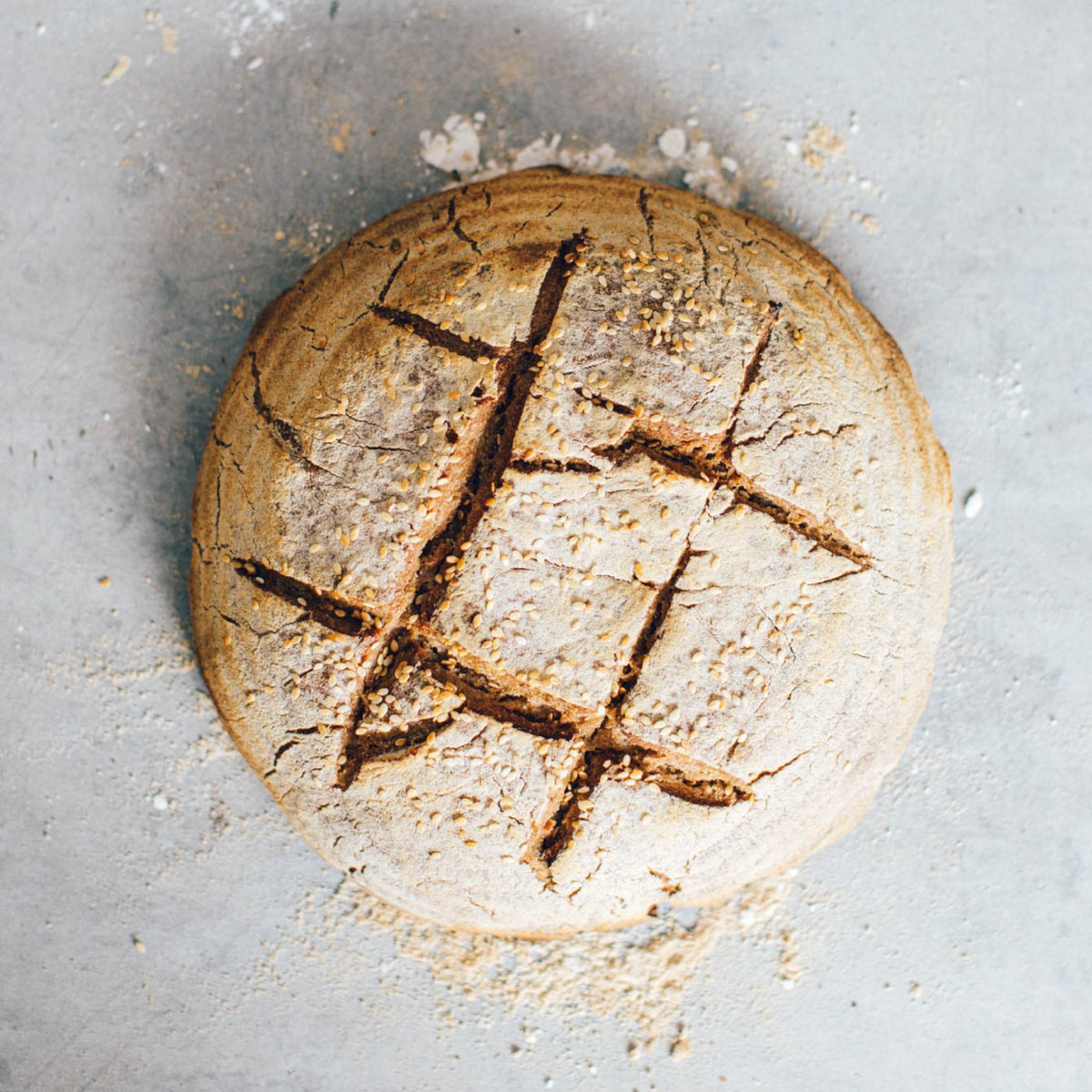 Round sourdough loaf of bread scored in a lattice pattern, turned out of the rattan basket
