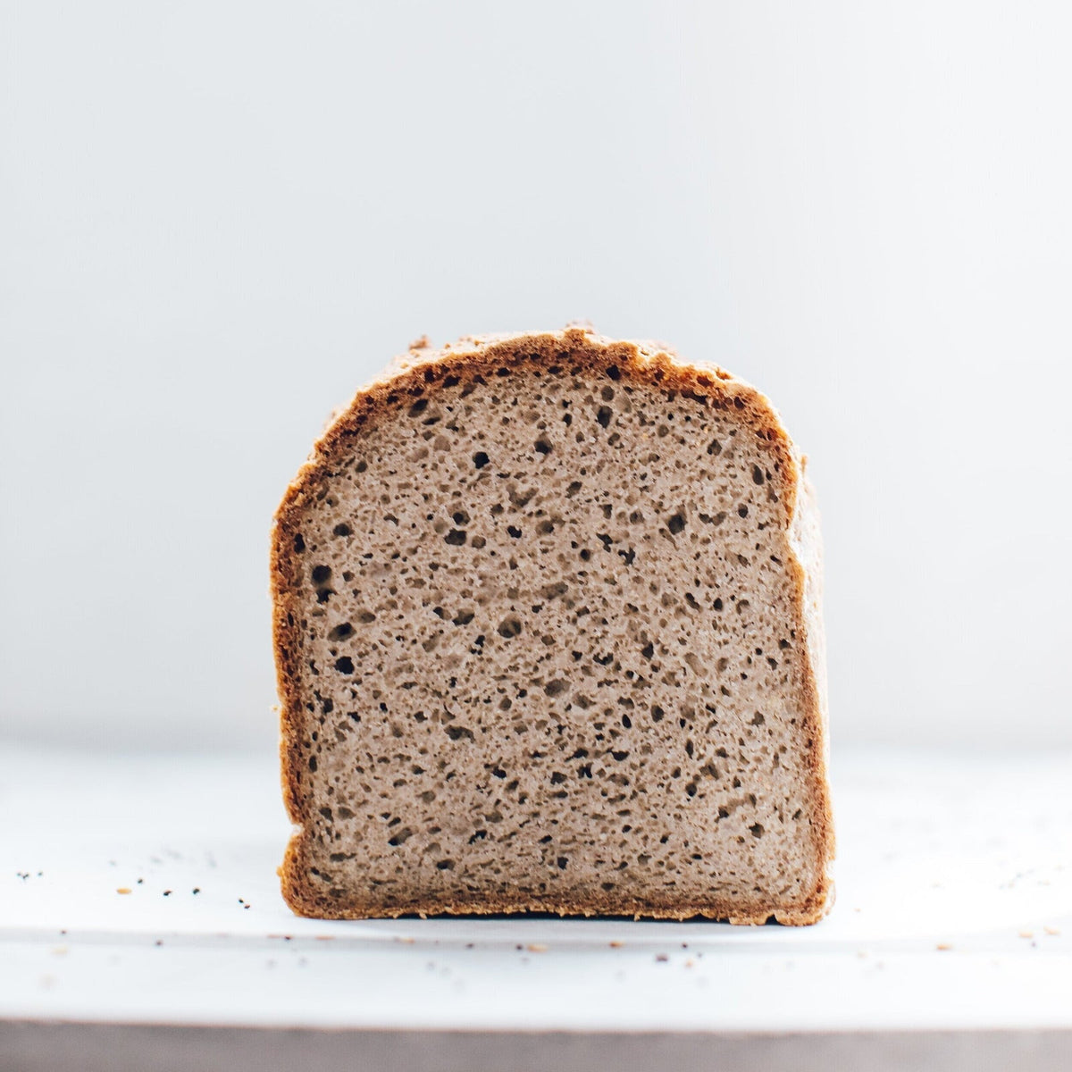 Thick slice of seeded loaf of bread baked using the Reusable Rectangular Loaf Tin Liner