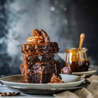 Stack of caramel brownies with sauce poured over, baked using the Reusable Sheet Cake Liner