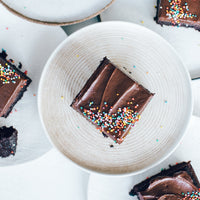 Square of chocolate slice topped with sprinkles on a ribbed plate, baked using the Reusable Sheet Cake Liner