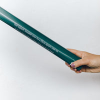 Hand holding the Reusable Square Cake Tin Liner in its slim green packaging tube