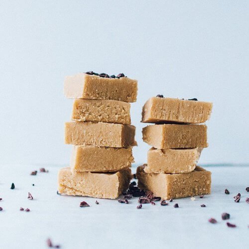 Stacks of caramel slice squares scattered with cacao nibs, made using the Reusable Square Cake Tin Liner