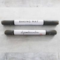 Two rolled Silicone Baking Mats in their branded tubes on a bench