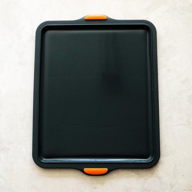 Silicone Baking Tray in charcoal with orange silicone handles, shown from above