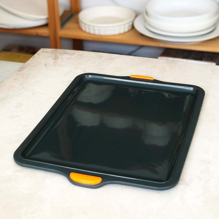 Silicone Baking Tray on a bench in front of open shelves of crockery
