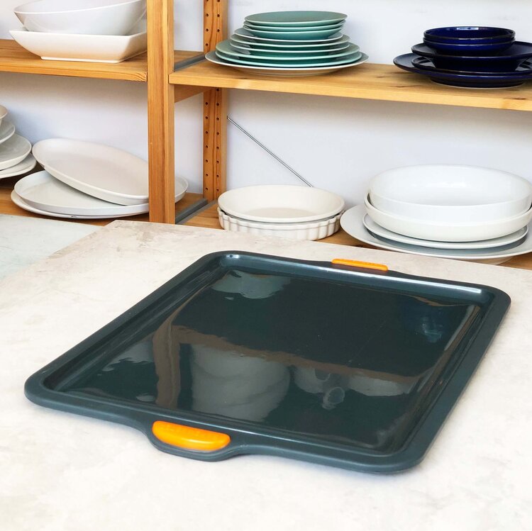 Silicone Baking Tray angled on a bench in front of shelves of plates and bowls