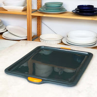 Silicone Baking Tray angled on a bench in front of shelves of plates and bowls