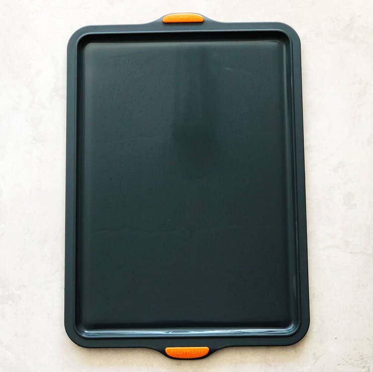 Silicone Baking Tray shown from above, its non-stick surface and orange grips visible