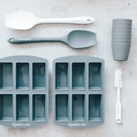 Two Silicone Bar Moulds trays with a spatula, cleaning brush and stacked cups alongside