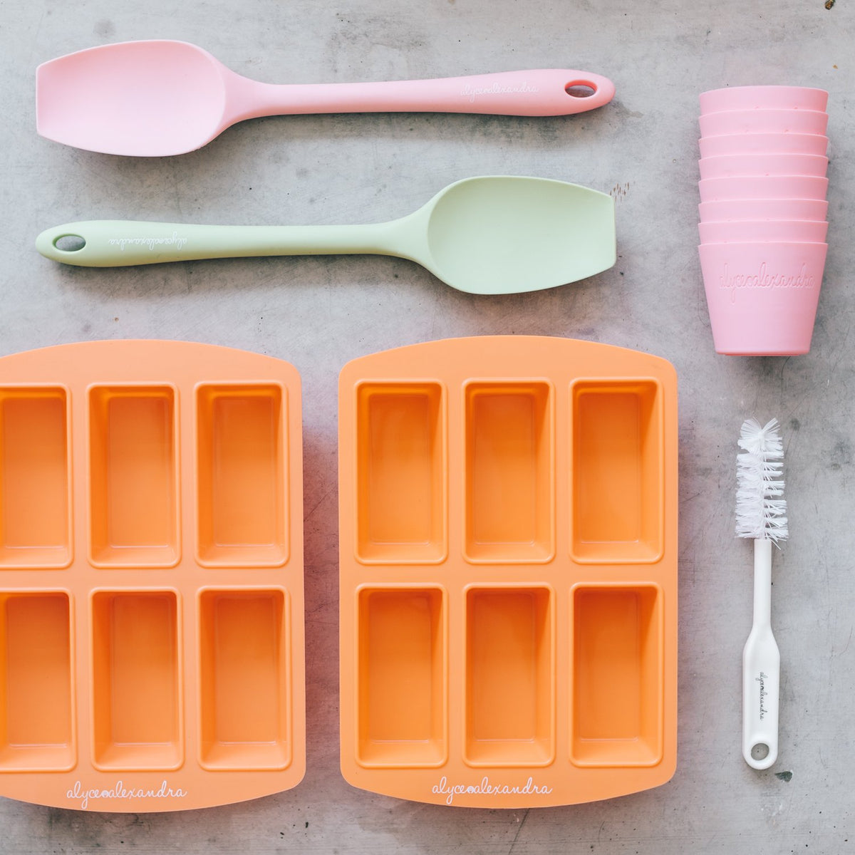 Terracotta Silicone Bar Moulds trays with pink and sage spatulas and a cleaning brush