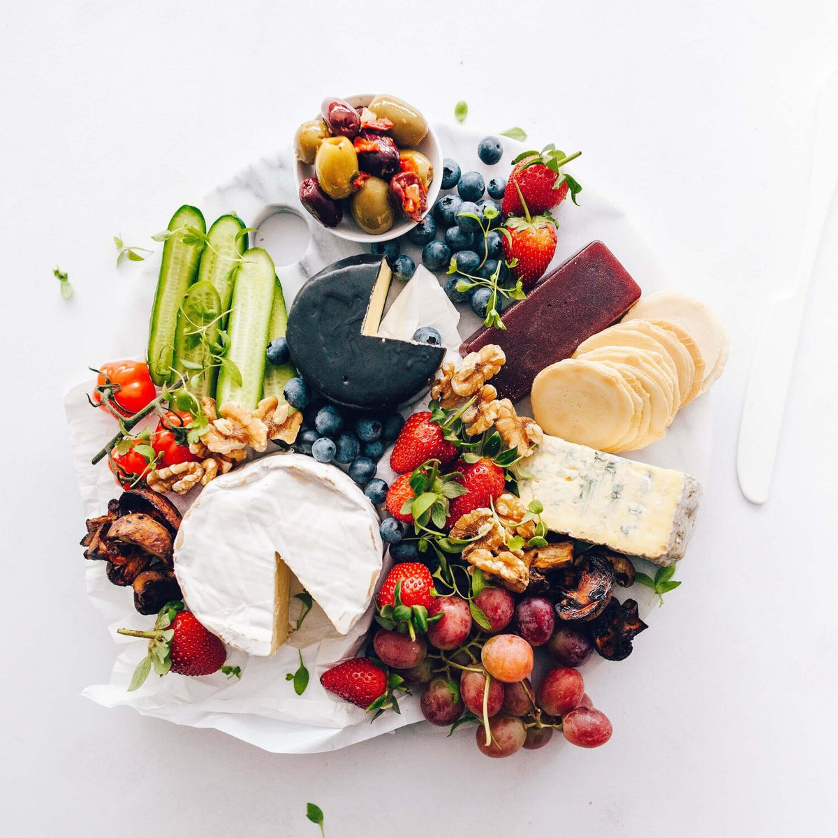 Grazing platter of cheese, fruit, nuts and vegetables on a round board