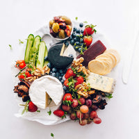 Grazing platter of cheese, fruit, nuts and vegetables on a round board