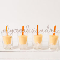 Four Silicone Dariole Moulds filled with mango dessert and wooden sticks, set in glasses