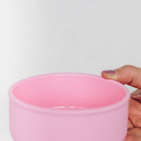 Hand holding the pink Silicone Nesting Bowl to show its flexible sides