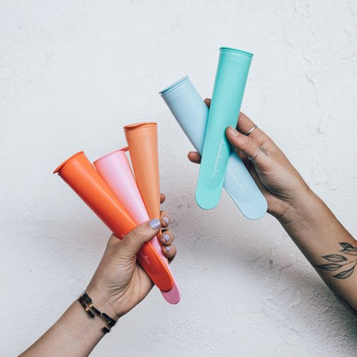 Hands holding the five Silicone Push Up Ice Cream Moulds in orange, pink, blue and green
