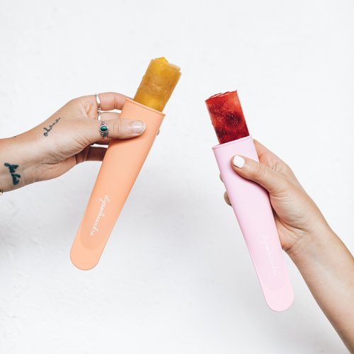 Two Silicone Push Up Ice Cream Moulds filled with mango and berry ice blocks, pushed part way up