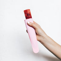 Hand holding a pink Silicone Push Up Ice Cream Mould with a berry ice block pushed up ready to eat