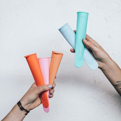 Hands holding the Silicone Push Up Ice Cream Moulds fanned out to show all five colours