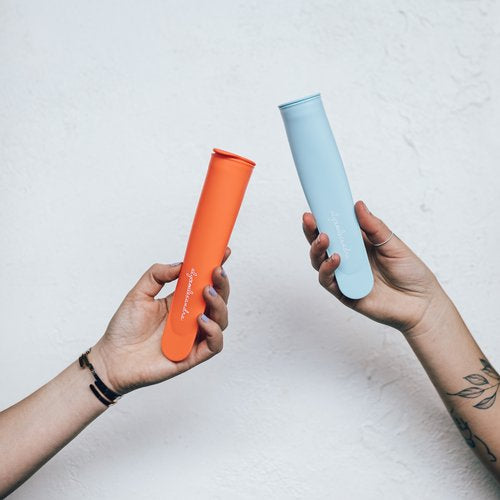 Two hands each holding a Silicone Push Up Ice Cream Mould, one orange and one blue