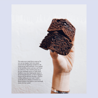 Hand holding a slice of dark chocolate sourdough loaf of bread