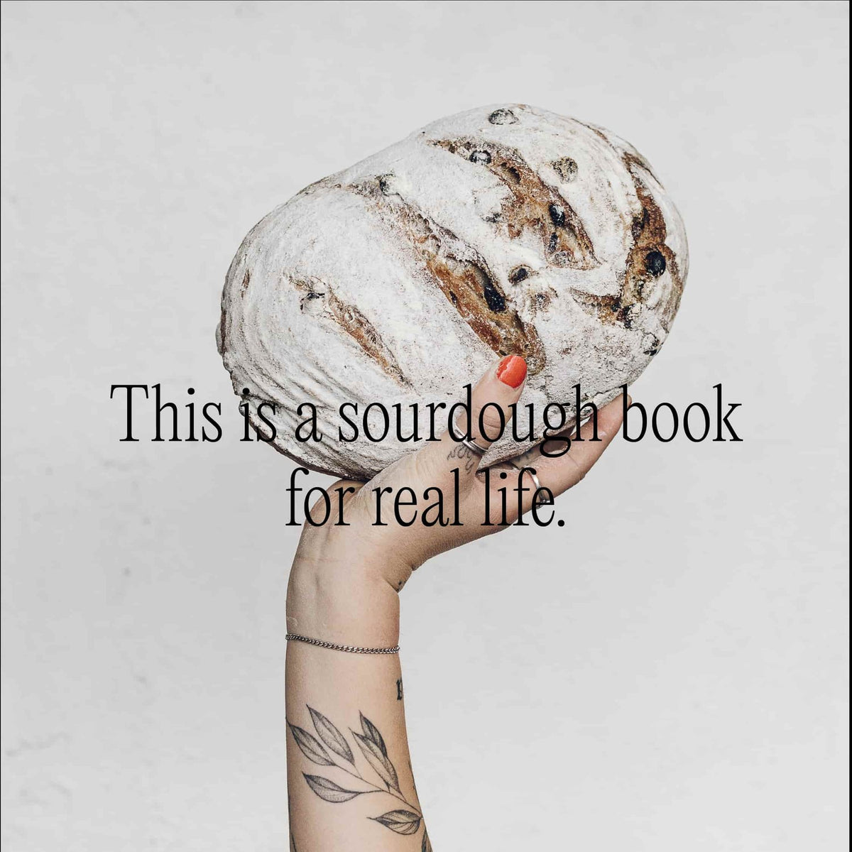 Hand holding up a round sourdough loaf of bread; this is a sourdough book for real life