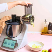 Hand feeding courgette into the Slicer and Shredder mounted on a Thermomix, with sliced vegetables collecting below