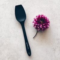 Charcoal Slow Cooker Spatula laid beside a purple dahlia