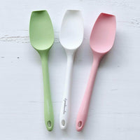 Three Slow Cooker Spatulas in sage green, white and pink laid on marble