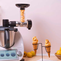 Soft-Serve Ice Cream attachment on a Thermomix with a filled cone in a stand and lemons alongside
