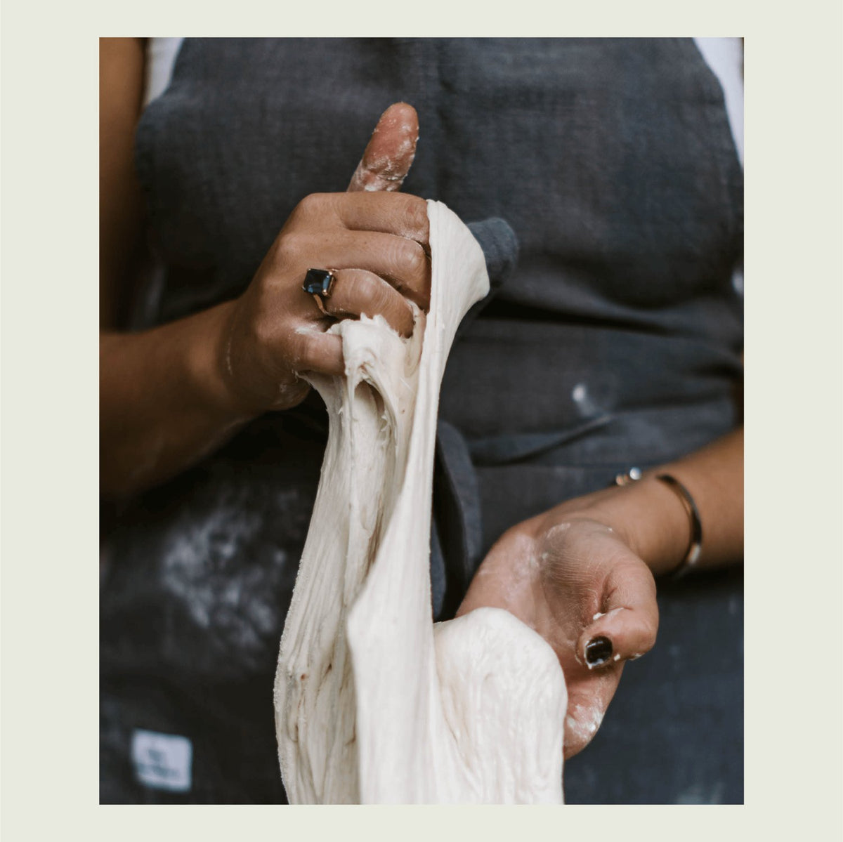 Hands stretching a length of sourdough dough to show its gluten development