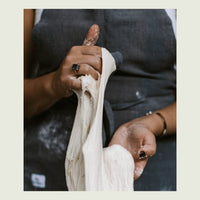 Hands stretching a length of sourdough dough to show its gluten development