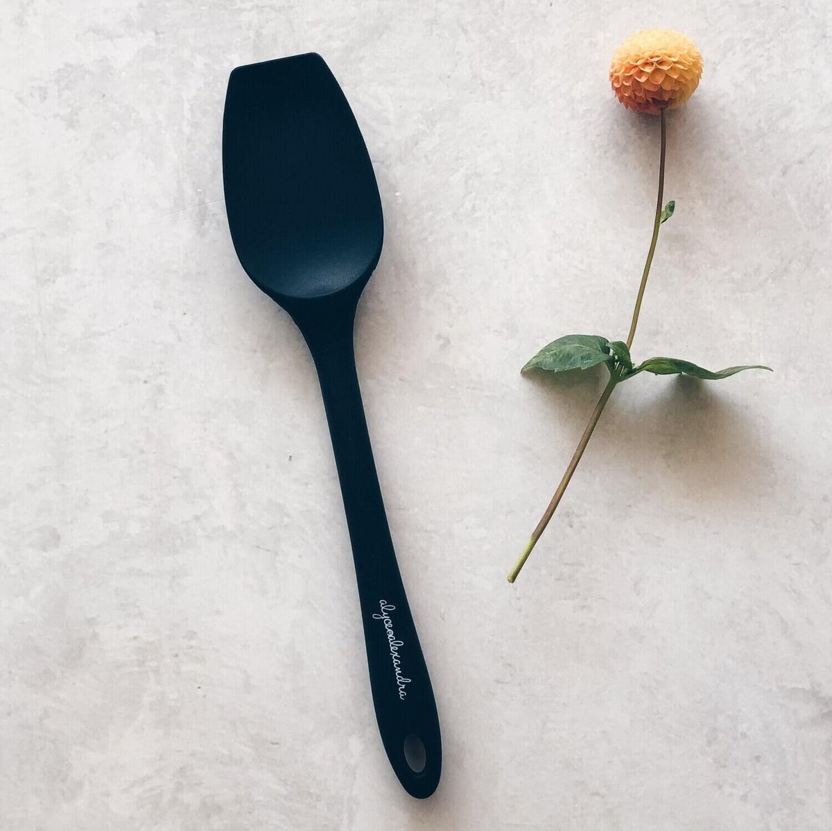 Charcoal Sourdough Spatula laid beside a dried flower