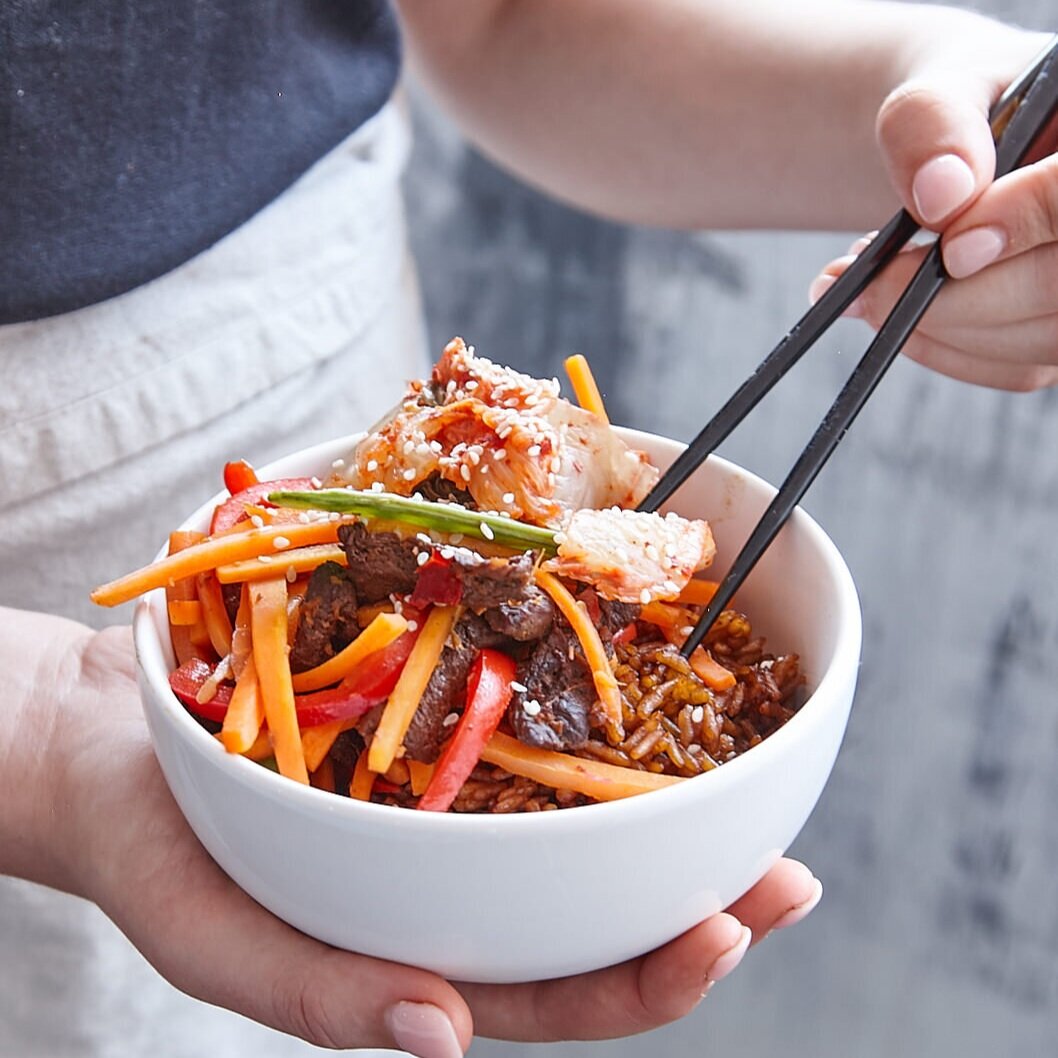 Hands serving a noodle and beef salad with chopsticks, made using the Starter Kit
